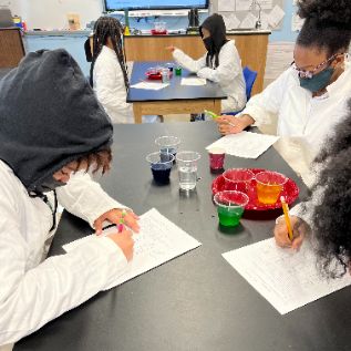  students working at a science table working with liquids